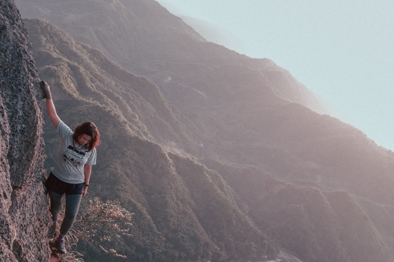 kobieta wspinająca się po górach - idąca zboczem góry